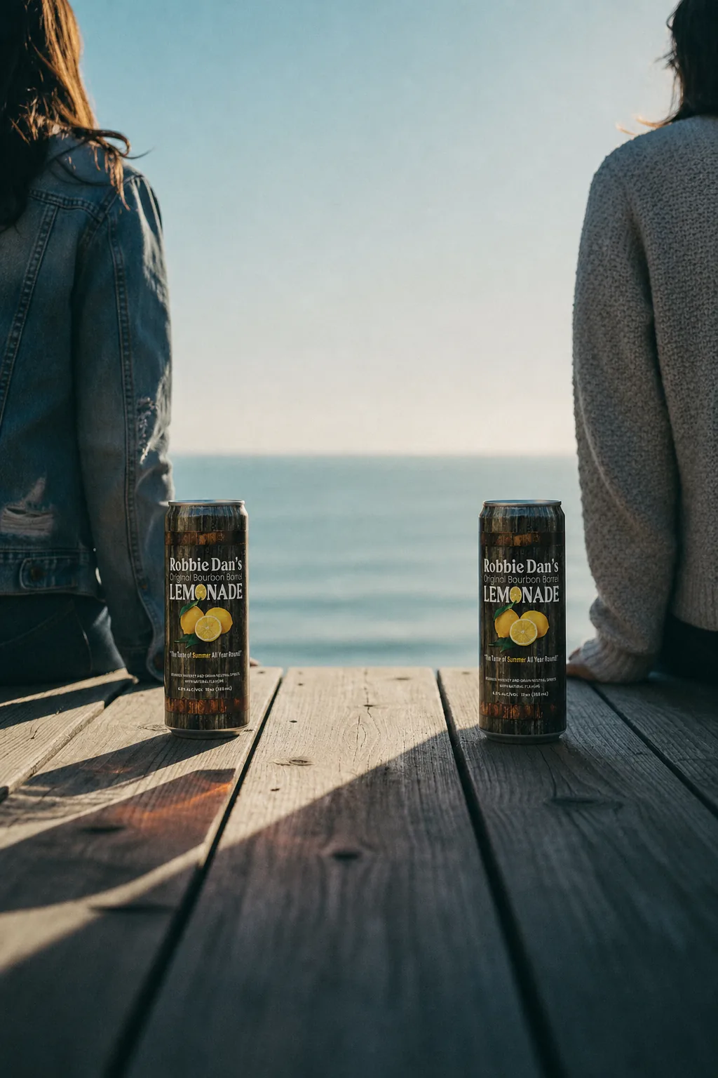 Two cans of Robbie Dan’s on a dock overlooking the ocean.